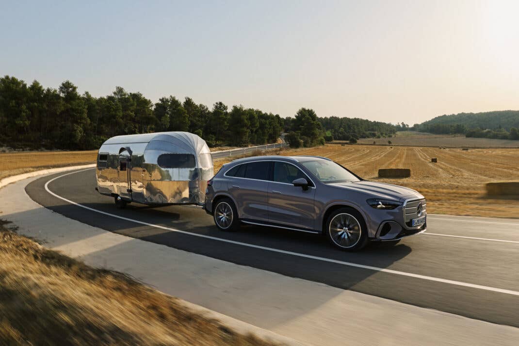 Mercedes-Benz GLC mit EQ-Technologie zieht einen Wohnwagen auf einer Straße.