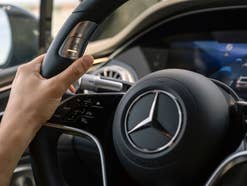 Hand an einem Lenkrad in einem Mercedes.
