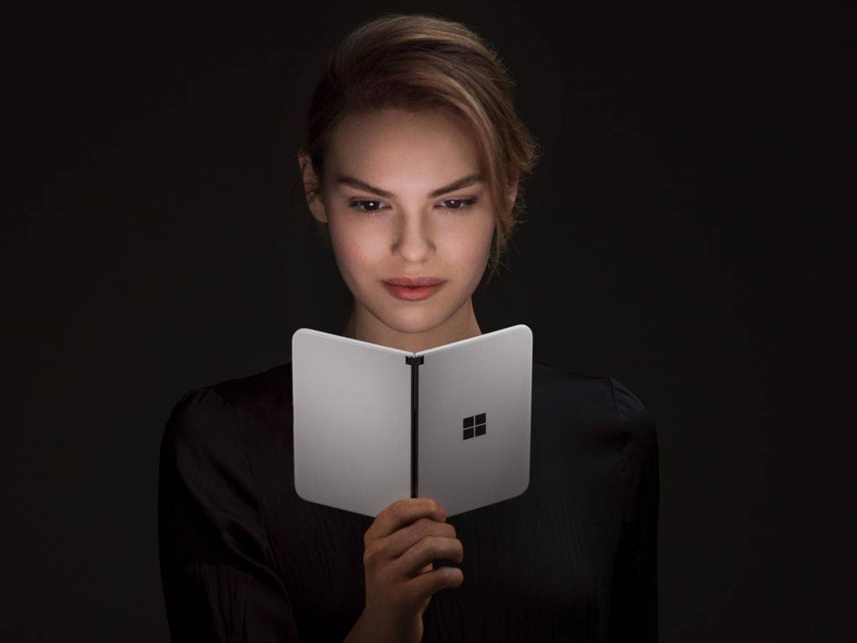 Microsoft Surface Duo in der Hand einer Frau die das Gerät wie ein aufgeklapptes Buch in der Hand hält.