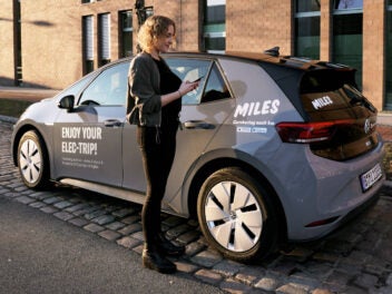 Frau öffnet mit ihrem Smartphone eine Carsharing-Wagen von Miles.