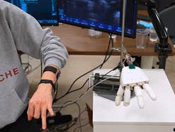 MIT-Ultraschall-Armband, Roboterhand, Gestensteuerung, Wearable-Prototyp, Ultraschall-Sensoren, KI-Steuerung, Human-Machine-Interface (HMI), Laboraufbau, Klavierspielen-Demo, Roboter-Prothese, MIT-Forschung.