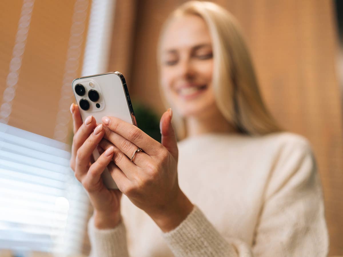 Blonde Frau nutzt ein Smartphone.