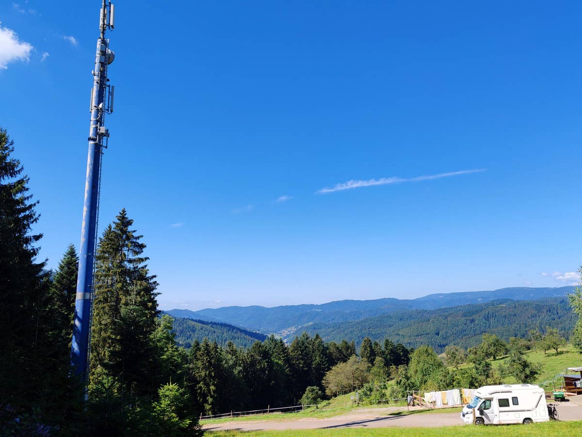 Ein Wohnmobil steht unter einer Mobilfunkantenne im Schwarzwald