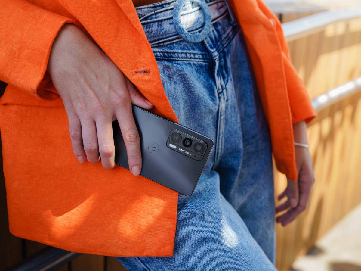 Das Motorola Edge 20 Smartphone in der Hand einer Frau, die es vor ihre Jeans hält