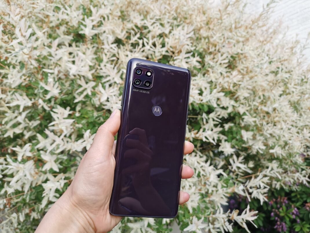 Die schwarze Rückseite des Motorola Moto G 5G vor einem weißen Busch