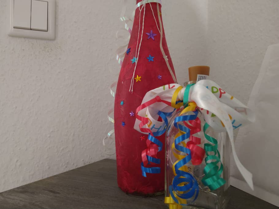 Eine Flasche mit Dekoration vor weißer Wand