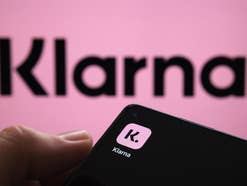 Klarna-App auf einem Smartphone mit Klarna-Logo im Hintergrund.