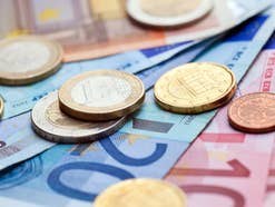 Euro-Münzen und Euro-Banknoten auf einem Tisch liegend in der Nahaufnahme.