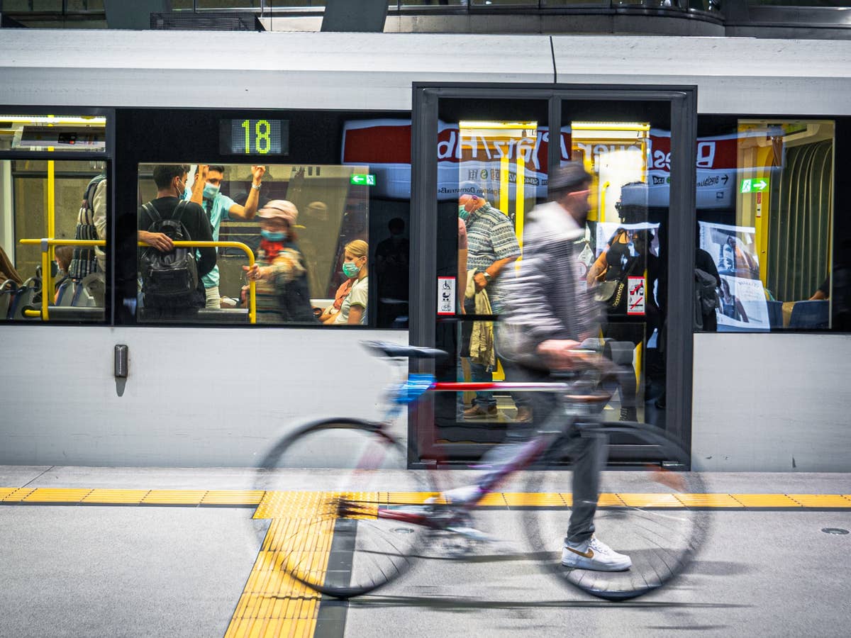 Mann mit Fahrrad läuft vor Straßenbahn auf Bahnsteig