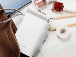 Nelko Etikettendrucker auf einem Tisch in einer Handtasche mit Maßen