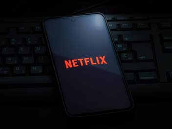 Smartphone mit Netflix-Logo liegt in der Dunkelheit auf einer Tastatur.