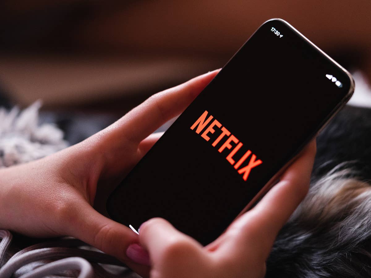 Das Netflix-Logo auf dem Bildschirm von einem Handy, das in der Hand gehalten wird.