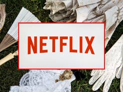 Netflix-Logo vor einem Hintergrund aus viktorianisch anmutenden Accessoires wie Fächern, Handschuhen und Broschen, die auf einer grünen Wiese liegen.