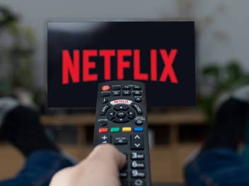 Netflix-Logo auf einem Fernseher hinter einer Fernbedienung.