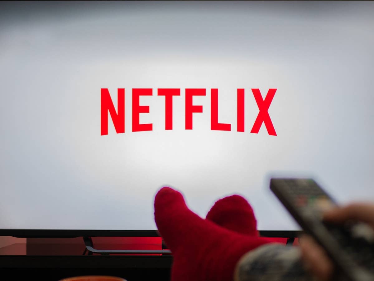 Netflix-Preiserhöhung verhindern Netflix-Logo auf einem Fernseher, Person im Anschnitt mit Fernbedienung in der Hand
