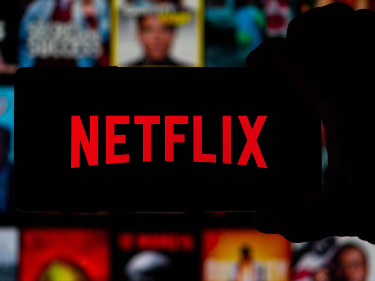 Netflix-Logo auf einem Smartphone vor Netflix-Oberfläche im Hintergrund