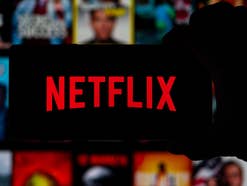Netflix-Logo auf einem Smartphone vor Netflix-Oberfläche im Hintergrund