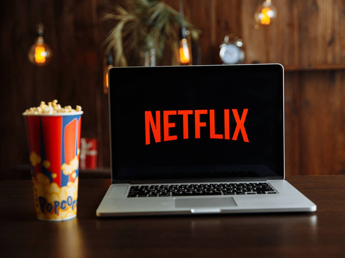 Netflix-Logo auf einem Notebook, das neben einer Schachtel Popcorn steht.