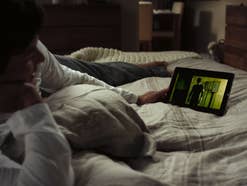 Mann liegt im Bett und schaut Netflix auf einem Tablet