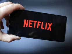 Netflix-Logo auf einem Smartphone, das eine Hand hält.