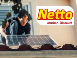 Jemand, der ein Solarmodul in der Hand hat und auf einem Dach steht. Oben rechts das Netto-Logo