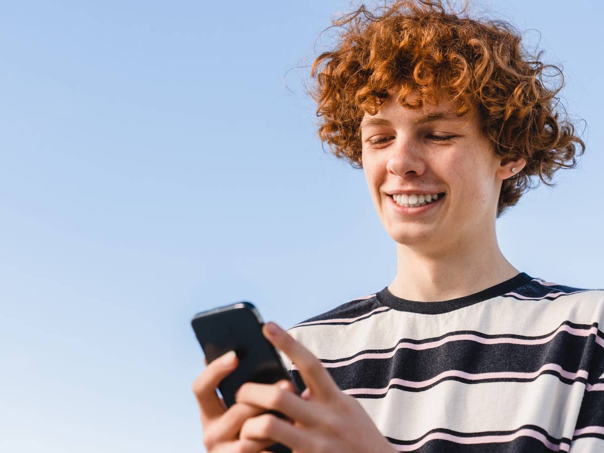 O2, Telekom oder Vodafone: Welcher Mobilfunkanbieter hat gutes Netz auf dem Land? Ein Mann blickt in sein Smartphone und lächelt.