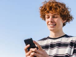 Ein Mann blickt in sein Smartphone und lächelt.