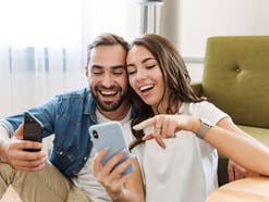 Mann und Frau nutzen Smartphones mit Freude.