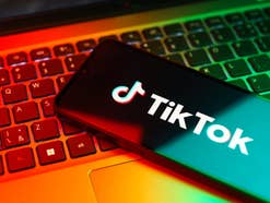 App von TikTok auf einem Smartphone, das auf einer Notebook-Tastatur liegt.