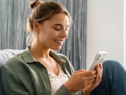 Frau lächelt bei der Nutzung eines Smartphones.