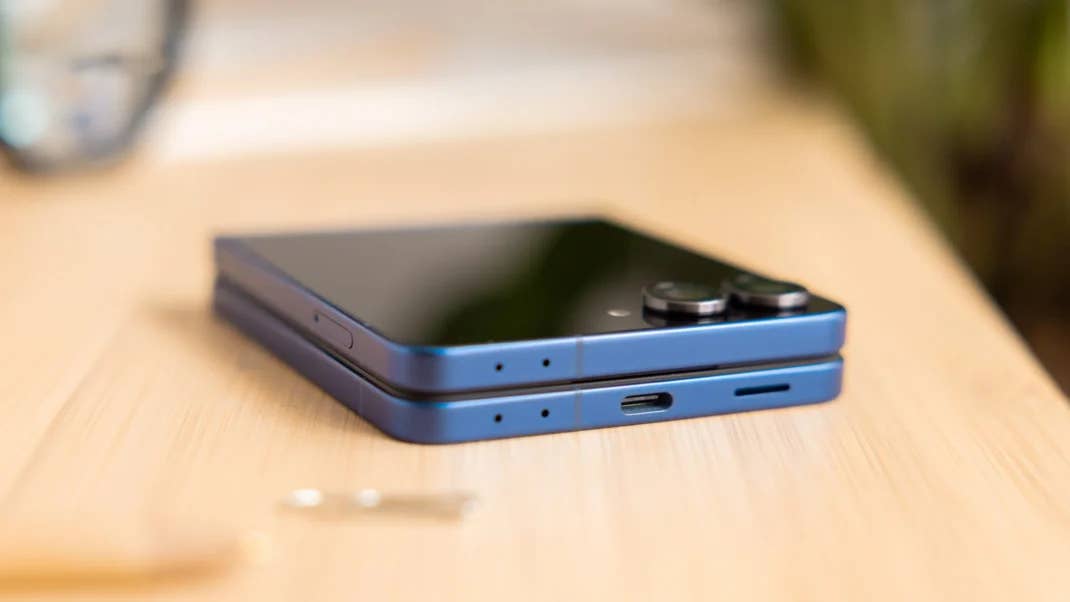 Ein blauer Samsung Galaxy Z Flip7 Smartphone liegt flach auf einer Holzoberfläche.