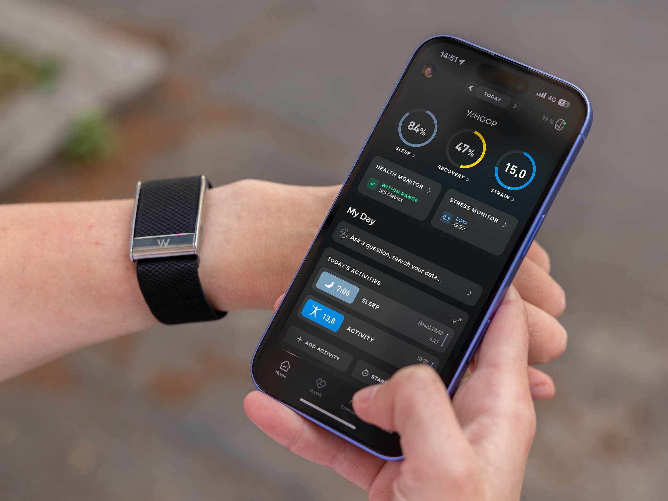 Eine Person hält ein Smartphone, das die Whoop-App zeigt, mit einem Fitness-Tracker am Handgelenk.