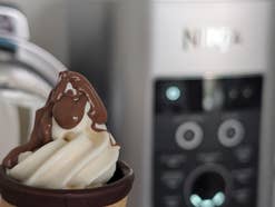 Im Vordergrund (scharf) ein Softeis mit Schoko-Topping, im Hintergrund (unscharf) eine Ninja-Eismaschine