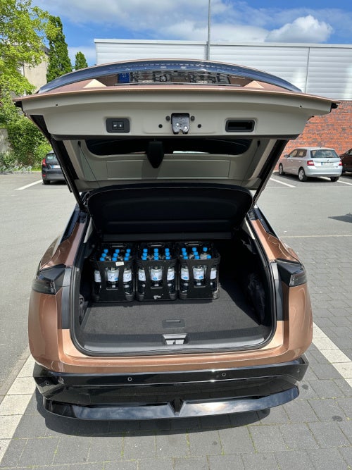 Kofferraum des Nissan Ariya mit drei eingestellten Getränkekisten.