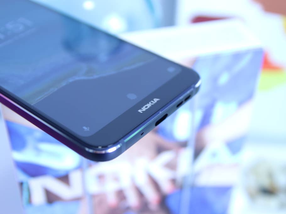 Handy Nokia 7.1 auf einem Tisch mit Gläsern im Hintergrund