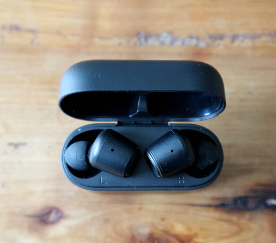 Die Nokia Noise Cancelling Earbuds im Ladecase auf einem Holztisch.