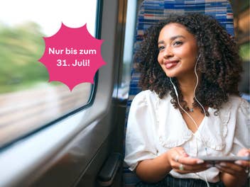 Frau sitzt in der Bahn mit dem Handy in der Hand