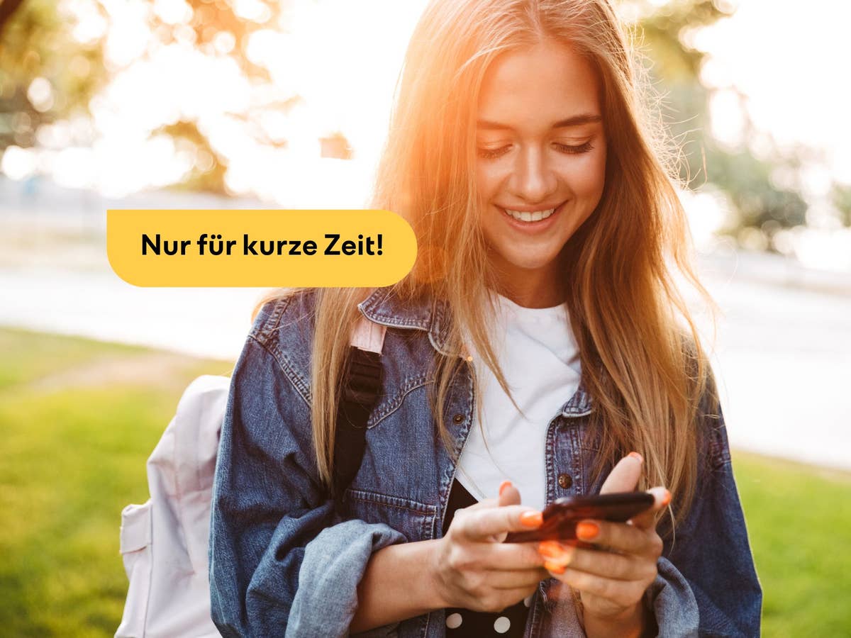 Junge Frau schaut lächelnd auf ihr Handy
