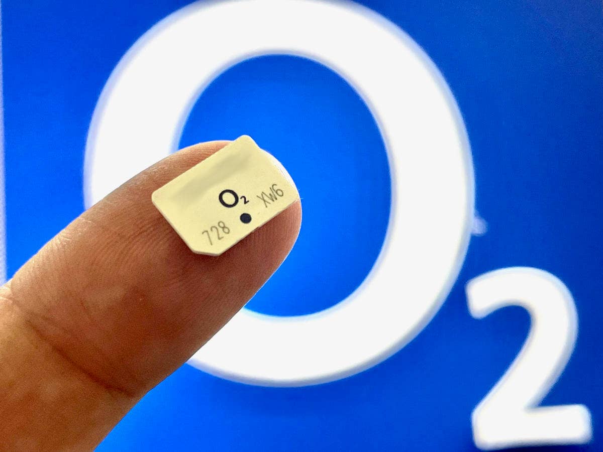 O2 SIM Karte auf Zeigefinger vor einem großen O2-Logo im Hintergrund