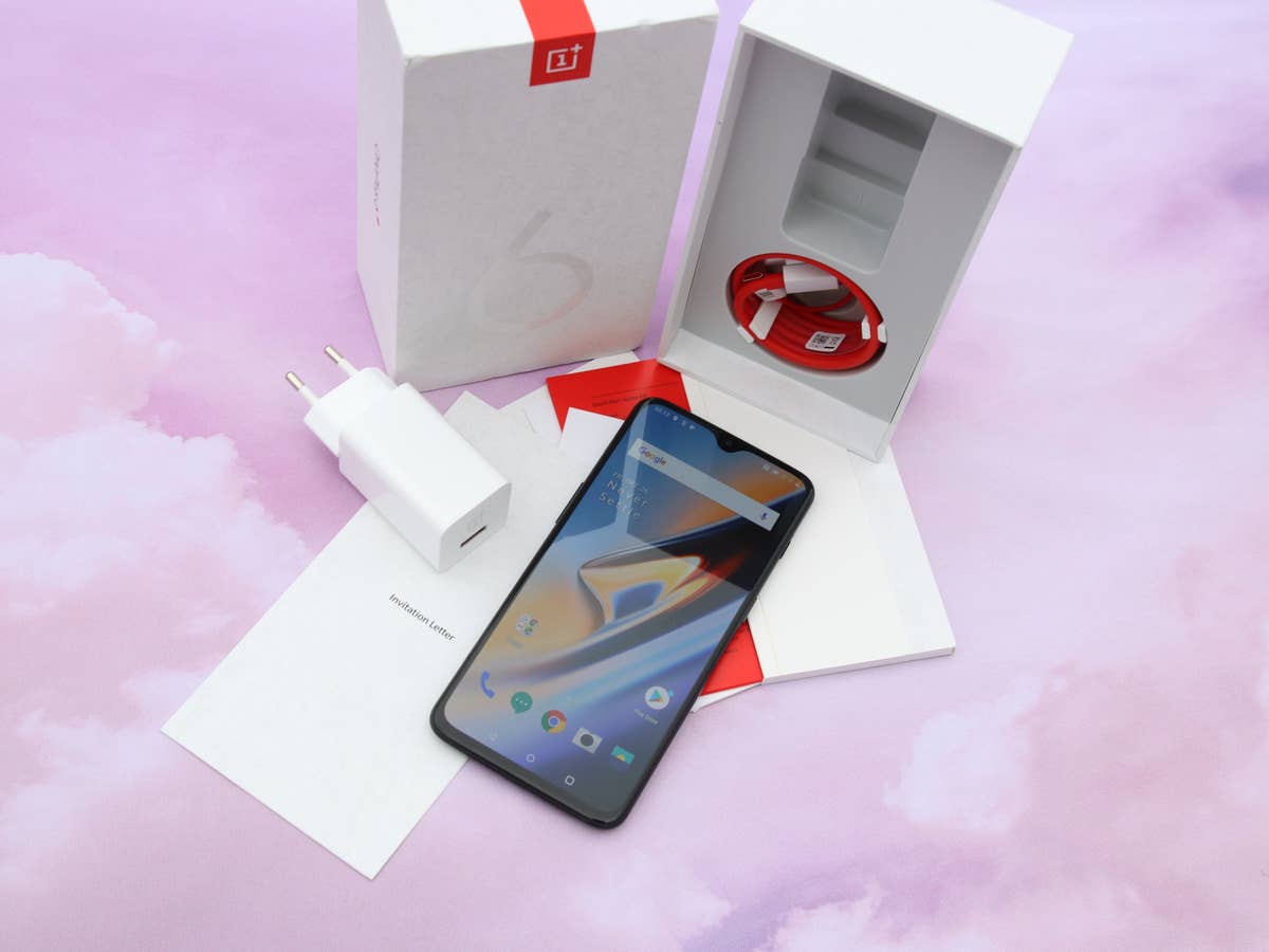 OnePlus 6T mit Zubehör und Verpackung auf rosa Grund