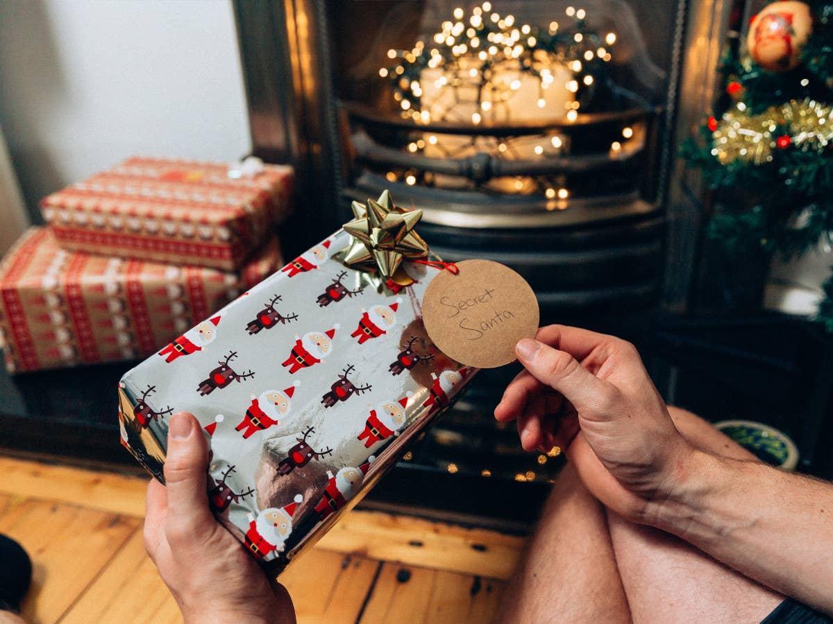 Ein Mann vor einem Kamin mit einem Weihnachtsgeschenk in der Hand, das ihm von einem Wichtel geschenkt wurde.