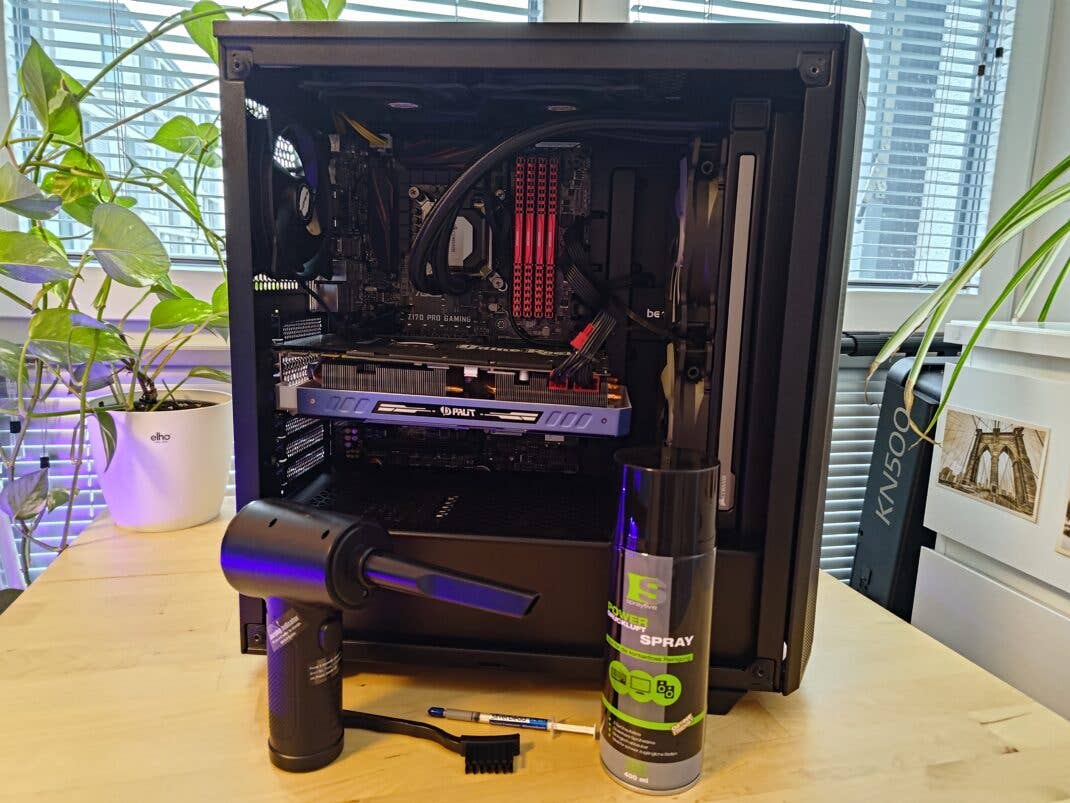 Mehrere Reinigungstools vor einem offenen Computer.
