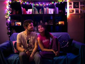 Ein junges Paar auf dem Sofa mit Weihnachtsbeleuchtung, die Weihnachtsserien bei Netflix gucken.