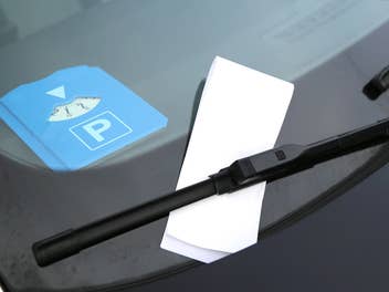 Parkscheibe liegt im Auto und davor ist ein Strafzettel