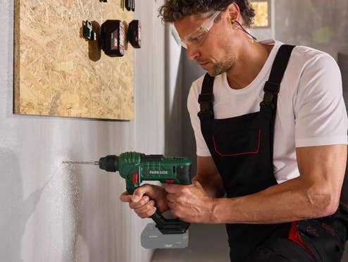 Ein Mann bohrt mit einem Parkside Akku-Bohrhammer