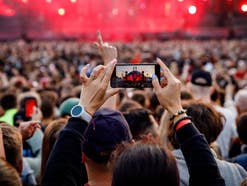 Person auf einem Festival hält das Handy hoch und filmt die Show