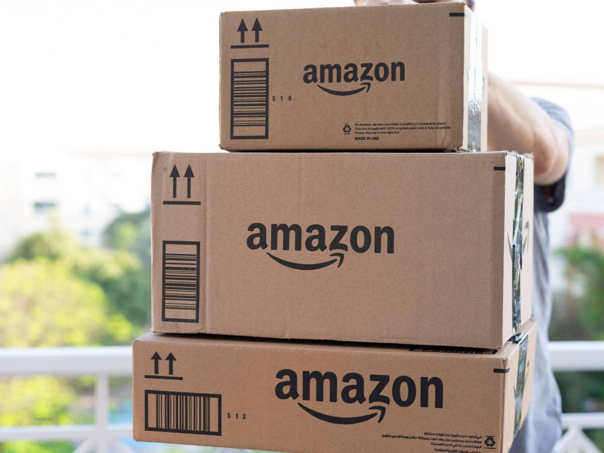 Amazon-Pakete Person hält drei Amazon-Pakete in den Händen und trägt sie in die Wohnung