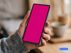 Person hält Smartphone mit pinkem Display in der Hand, KI-generiert
