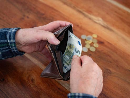 Person holt 5 Euro aus dem Geldbeutel heraus