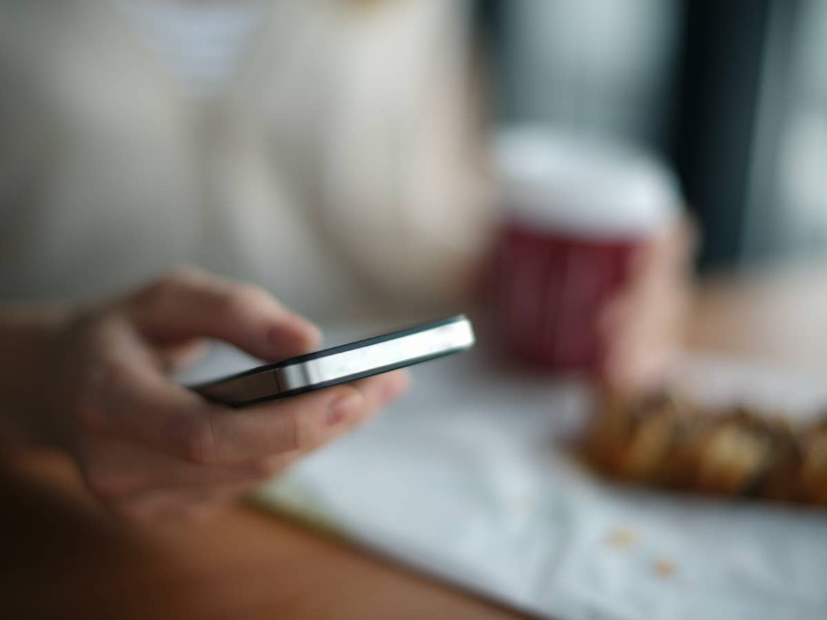 Person hält Handy mit Signal drauf in der Hand, auf dem der Fokus der Kamera liegt, Hintergrund ist verschwommen.